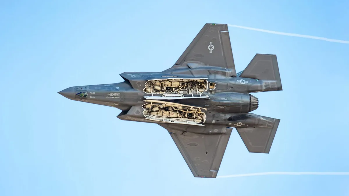 F-35 fighter jet in flight with weapon bay doors open.