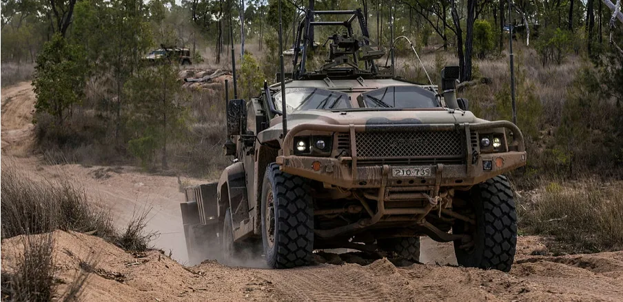 Hawkei protected vehicle driving along a dusty track.